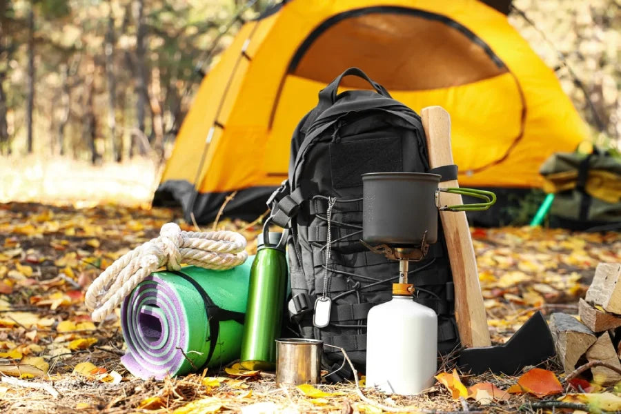 survival kit and camping tent in autumn forest