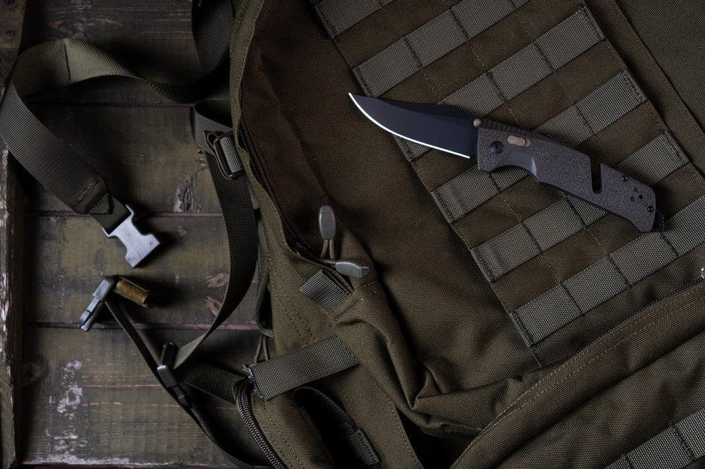 Military knife laid against MOLLE webbing